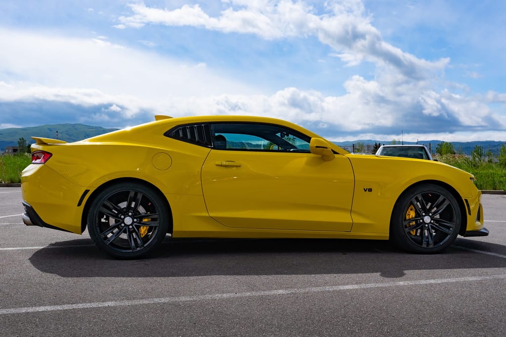 Страничен профил на Camaro, планини и облаци на фона